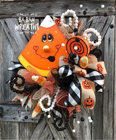 halloween wreath, candy corn wreath, and halloween door decor on display in front of an old wooden door