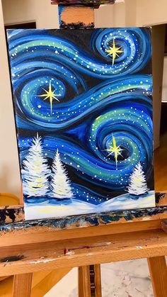 an easel with a painting on it that has stars in the sky and trees