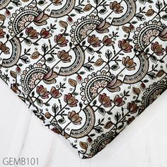 a white and brown paisley print tie laying on top of a white sheet with black trim