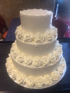 a three tiered cake with white roses on it