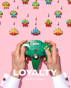 a person holding a video game controller in front of a pink background with the words loyatty on it