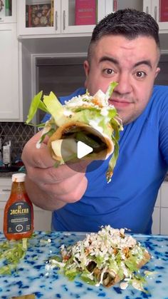 a man holding up a sandwich on top of a table