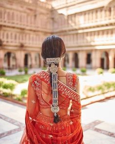 the back of a woman's head wearing an orange sari with intricate jewelry