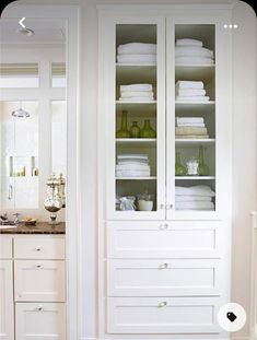 a bathroom with white cabinets and towels on the shelves in front of it, along with a marble counter top