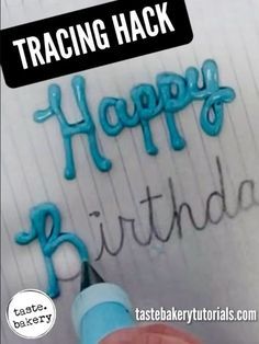 a person writing happy birthday on a sheet of paper with blue icing and a marker