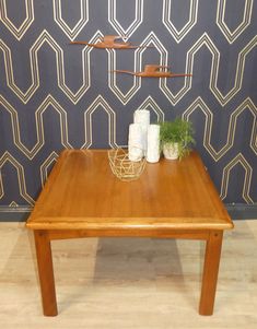 a wooden table sitting in front of a wall with geometric designs on the walls behind it