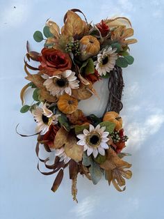 a wreath with flowers and leaves hanging on the wall