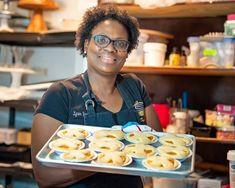 a woman is holding a tray of pies