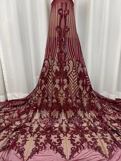 a red and gold dress on display in front of a white curtain