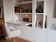 a white desk and chair in a room with bookshelves on the wall behind it