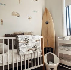 a baby's room with a surfboard on the wall and a crib next to it