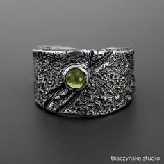 "Scar Peridot Ring, Middle Ages Style Rough Ring, Green Gem Viking Ring, Contemporary Wide Peridot Ring, Large Raw Unisex Ring, Villain Ring Pure faceted peridot shines so brightly in this raw reticulated scar ring. Black patinated and polished. Materials:  Sterling silver (925 silver), peridot Dimensions of the stone:  3 mm ( 1⁄8 inch) Dimensions of the ring: 5 - 22 mm (13⁄64 - 55⁄64 inch) Weight: 12,83 g (0,45 oz) Size:  Europe 16, France 56, Great Britain P, USA 7 ½, Germany 17 ¾, Japan 15 The ring is adjustable, its size can be changed (from size 5 to size 7 ½). Other sizes are made to order. Please check out the detailed size charts for S, M, and L sizes in the last photos. Please try on a 9 mm (23⁄64 in) wide ring to determine the correct size. Patina is not a permanent coating.  The Handmade Peridot Rings For Anniversary, Green Handmade Fusion Rings, Rough Ring, Chrysocolla Ring, Urban Jewelry, Green Gem, Viking Ring, Middle Age Fashion, Green Gems