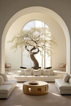 a living room with white couches and a large tree in the middle of it