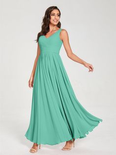 a woman wearing a long green bridesmaid dress with straps and pleaed skirt