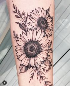 a sunflower tattoo on the leg with black and white flowers in front of it