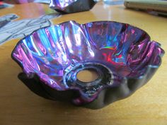 a purple glass bowl sitting on top of a wooden table next to a laptop computer