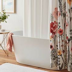 a bath tub sitting on top of a wooden floor next to a shower curtain and rug