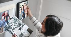 a woman looking at pictures on the wall with her hands holding them in front of her face