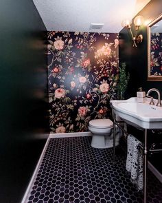 a black and white bathroom with floral wallpaper on the walls, toilet and sink