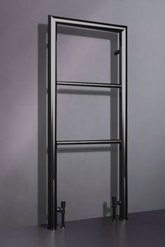 a metal shelf with three bars on it in front of a gray wall and floor