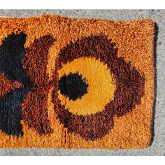 an orange and black rug on the ground with two circles in the shape of flowers