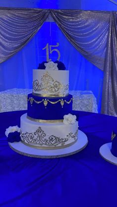 a blue and white wedding cake sitting on top of a purple table cloth covered table