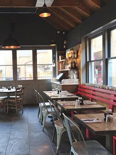 tables and chairs are lined up against the wall in an empty restaurant with large windows