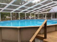 an above ground swimming pool is shown in this backyard area with decking and glass walls