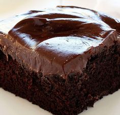 a piece of chocolate cake sitting on top of a white plate covered in frosting