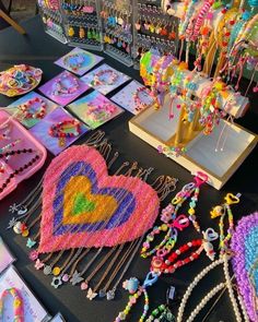 a table topped with lots of beads and necklaces next to boxes filled with jewelry