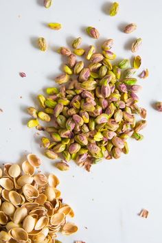 pistachios and peanuts on a white surface