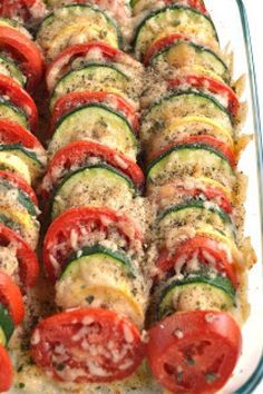 a casserole dish filled with sliced cucumbers, tomatoes and other veggies