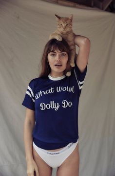 a woman with a cat on her head wearing a t - shirt that says what would dolly do