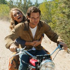 a man and woman riding on the back of a motorcycle