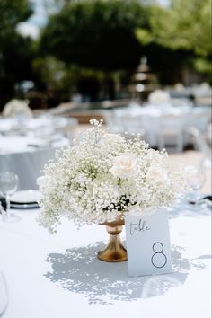 a table with white flowers in a vase on it and a sign that says table 8