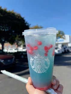 someone holding up a starbucks drink with cherries on it