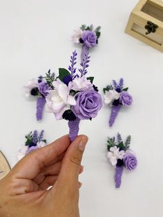 someone is holding some purple and white flowers in front of the other pieces of paper