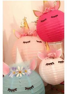 three paper lanterns with unicorn faces and flowers on them, one is pink the other is blue