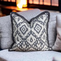 a gray and white pillow sitting on top of a couch next to a fire place