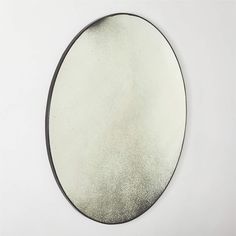 a round mirror on a white wall with black border around it and the reflection of an object in the mirror