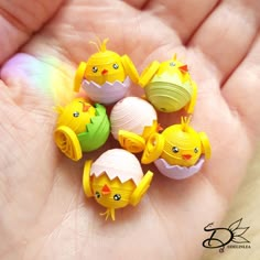 small yellow and green plastic chicks sitting on top of each other in a persons hand