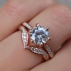 a woman's hand holding a ring with an aqua blue and white diamond in it