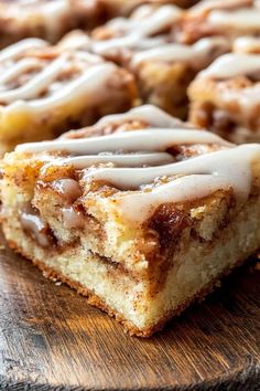 cinnamon roll with icing sitting on top of a wooden cutting board