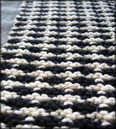 a black and white crocheted rug on the floor