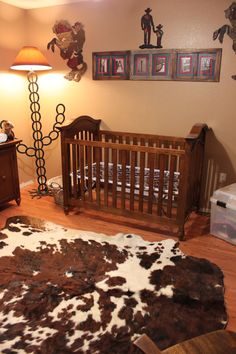 a baby crib in the middle of a room with pictures on the wall above it