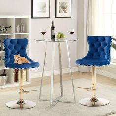 two blue chairs sitting next to each other in front of a table with wine glasses on it