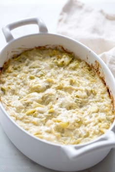 a white casserole dish filled with cheese and sauce on top of a table