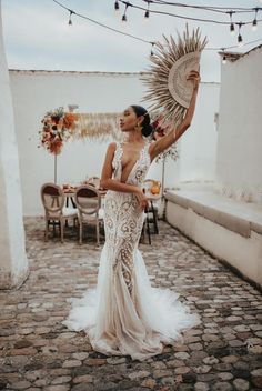 a woman in a wedding dress holding up a large sun - shaped fan on her head