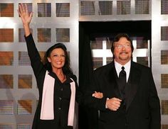 two people standing in front of a wall with crosses on it and one person raising their hands up