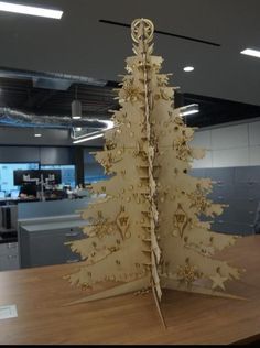 a cardboard christmas tree sitting on top of a wooden table next to an office cubicle